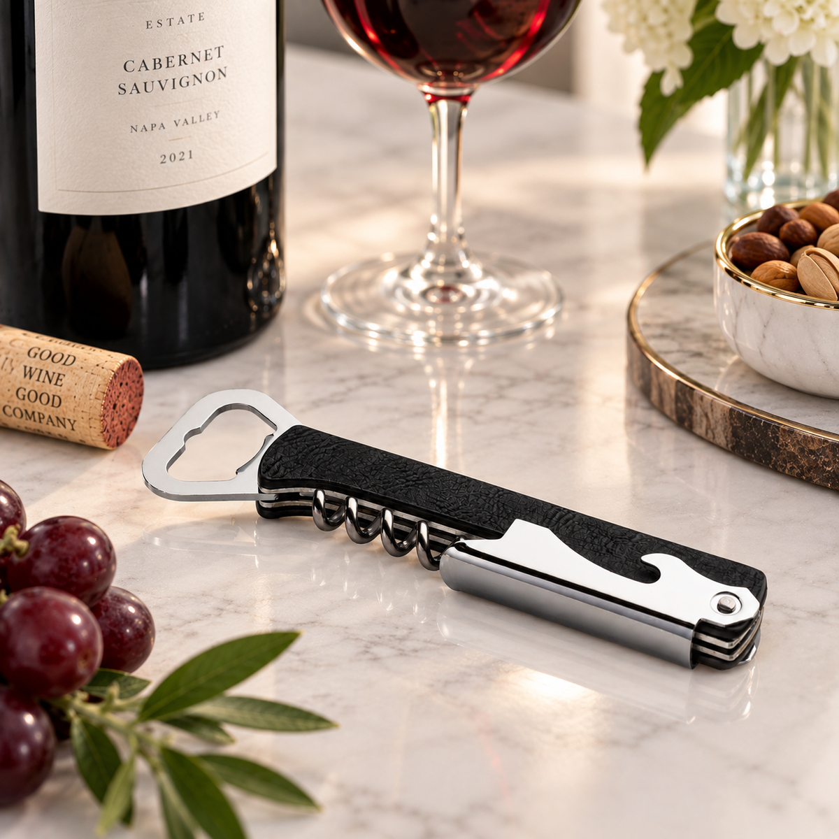 Leather corkscrew on a table with wine, grapes, nuts.