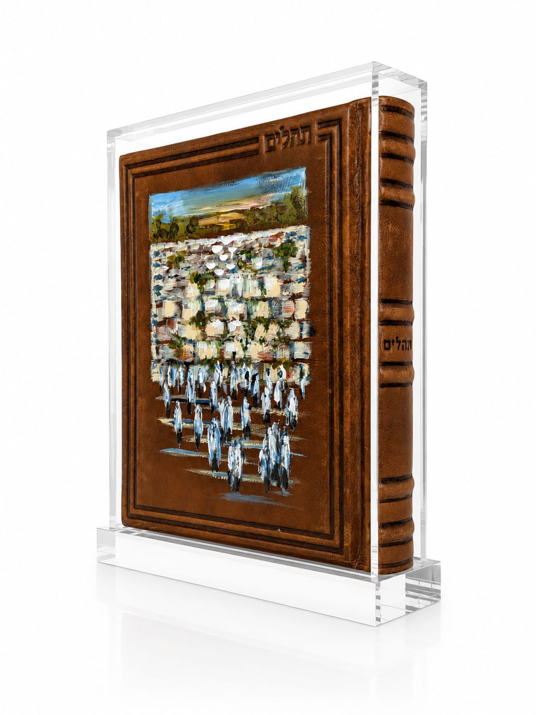 A clear acrylic display block holding a miniature brown leather tehillim with a painted illustration of a stone wall and people on the front cover, shown on a white background - Zstander