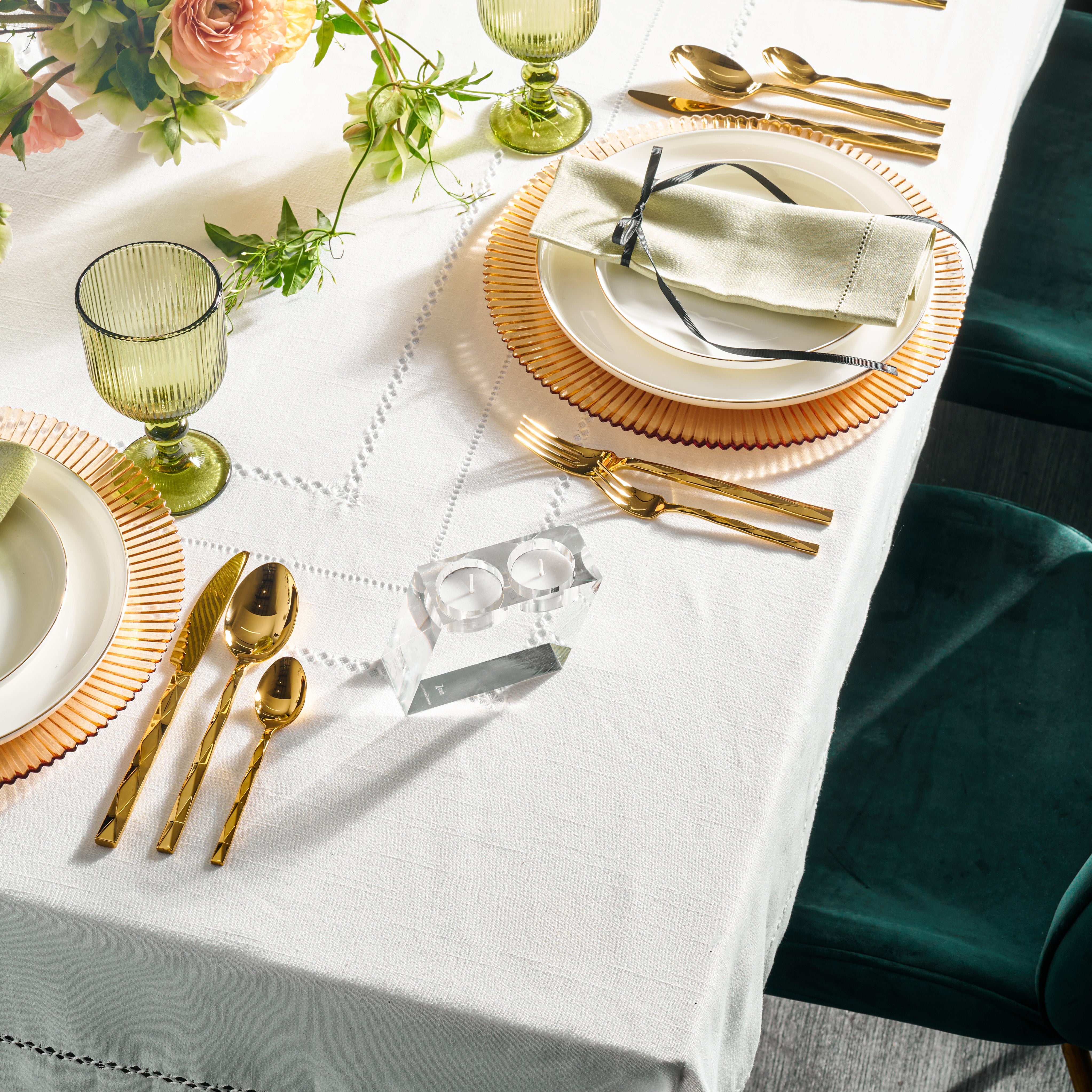 A set table with white tablecloth featuring clear lucite candle holders on the table among other decorative tableware - Zstander