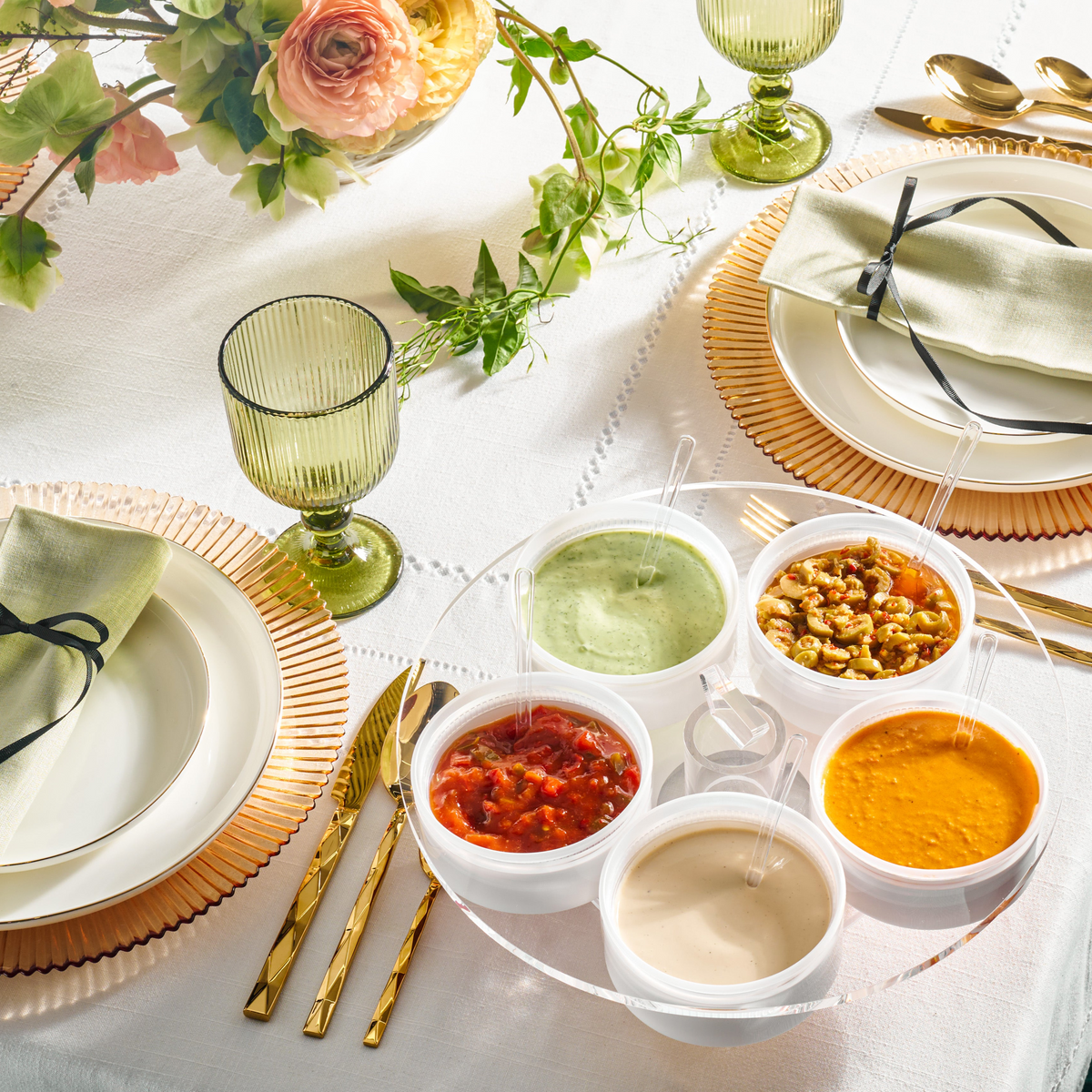 Elegant table setting with small dishes of food and green glasses on a white tablecloth - Zstander