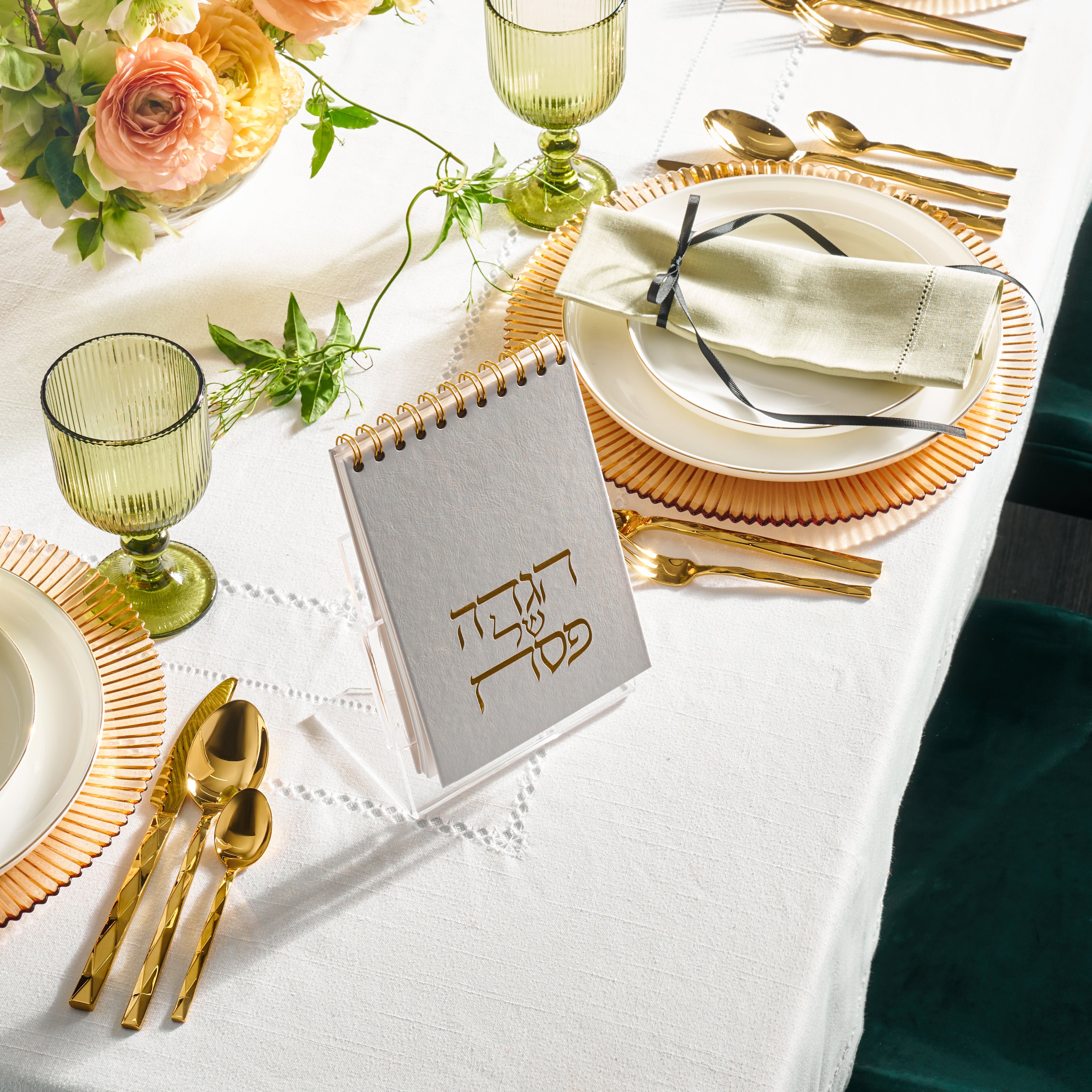 Top view of a spiral haggadah on a set table with plates, napkins, cups from Zstander