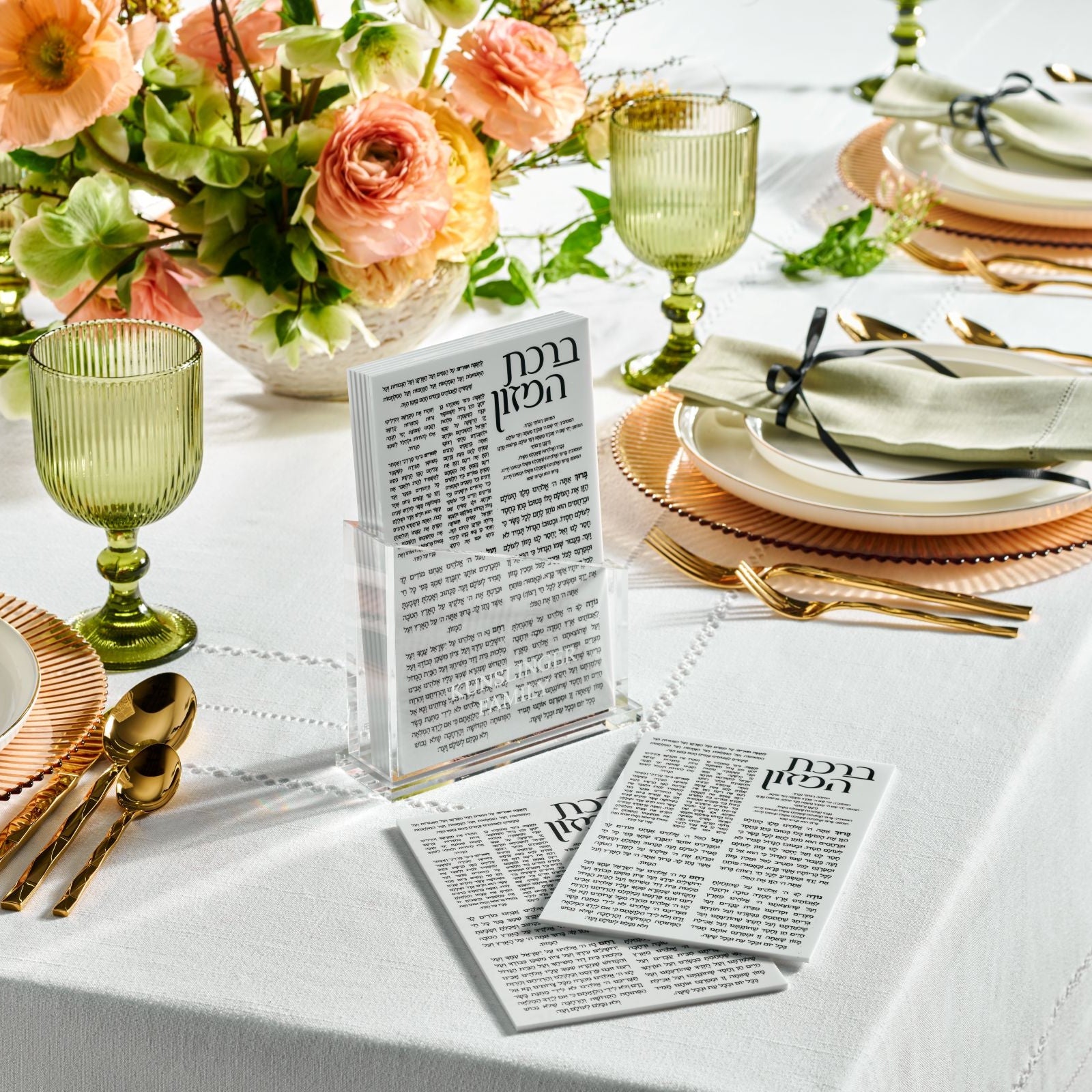 Elegant table setting with floral centerpiece, green glasses, and angled bencher set on a set table -Zstander