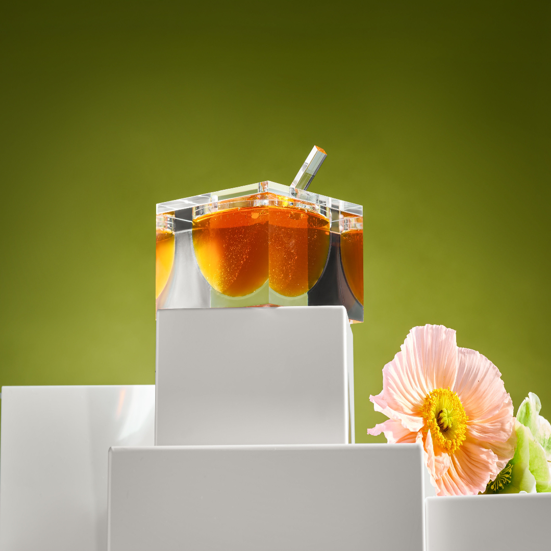 Clear lucite honey dish with honey and a pink flower on a green background - Zstander