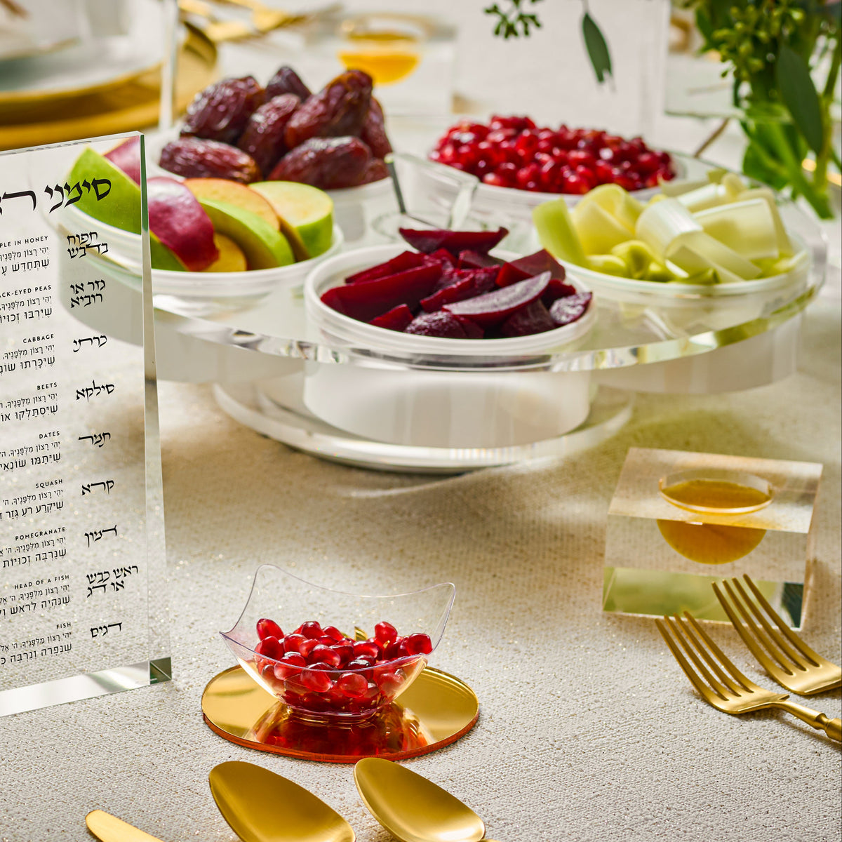 Table setting with a clear simanim card, gold cutlery, and fruit platter on a lazy Suzan tray - Zstander