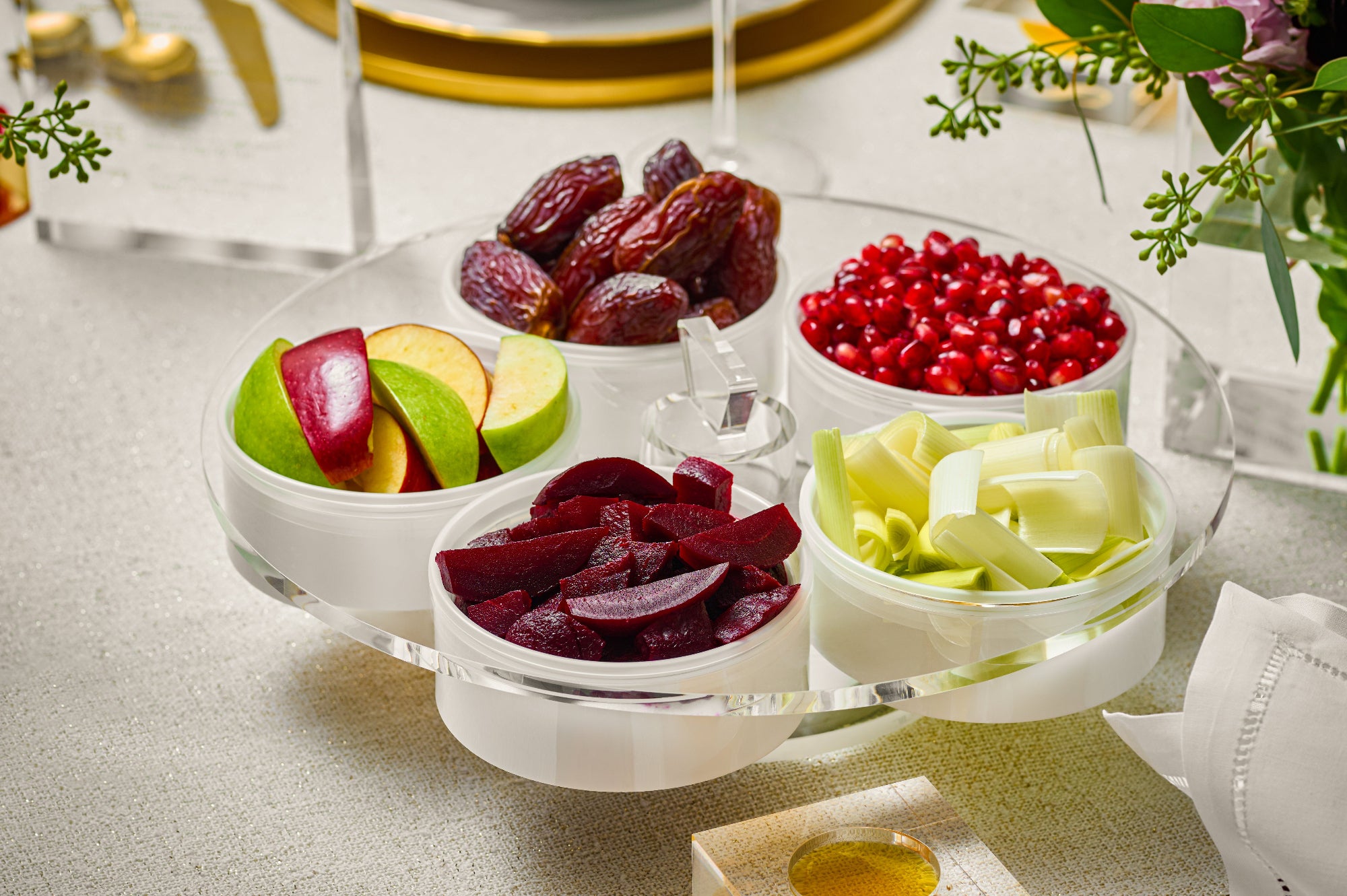 Assorted dried fruits and vegetables on a clear glass tray with a white napkin and floral decorations - Zstander