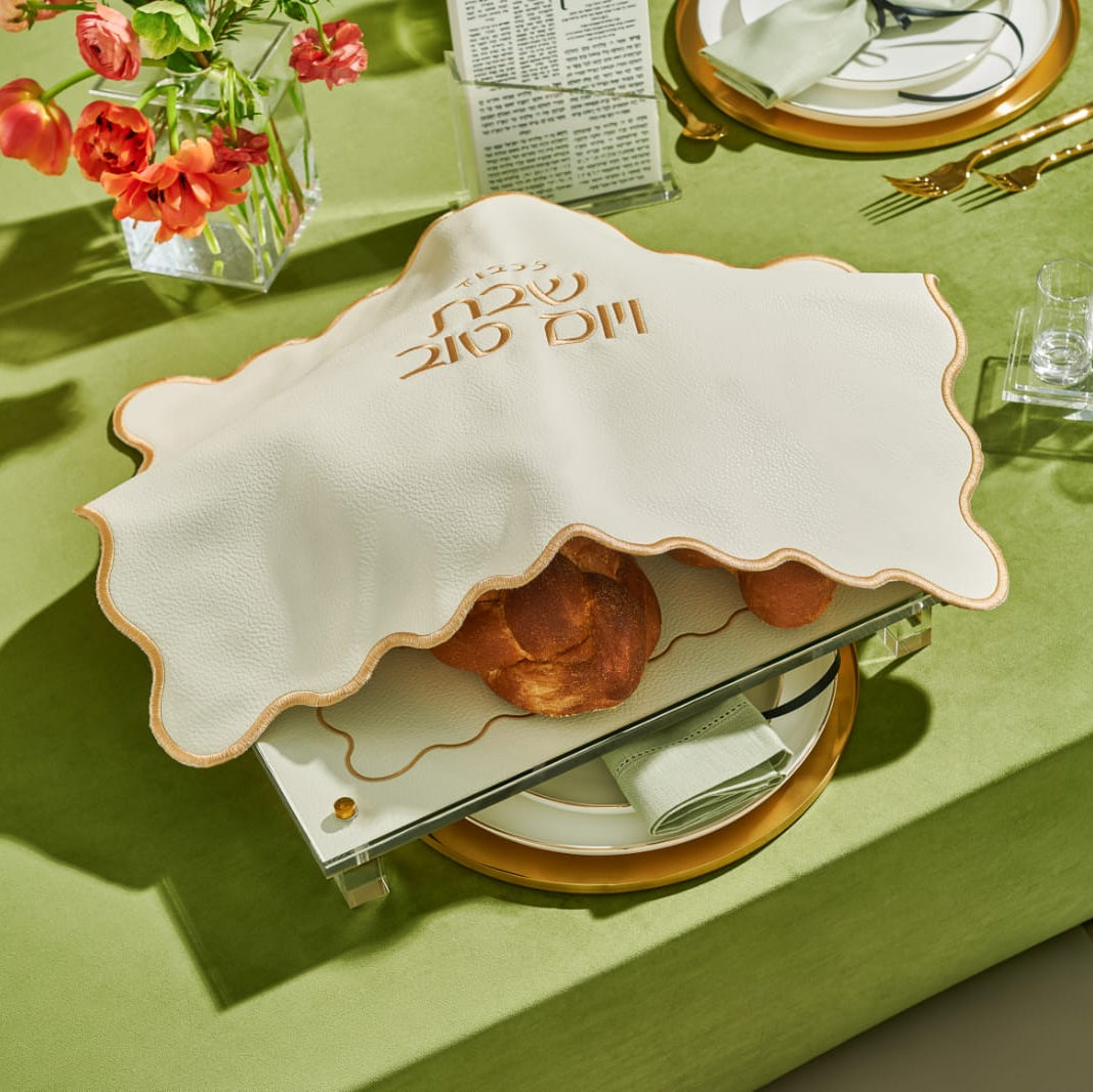 Decorative table setting with a challah and place settings on a green tablecloth - Zstander