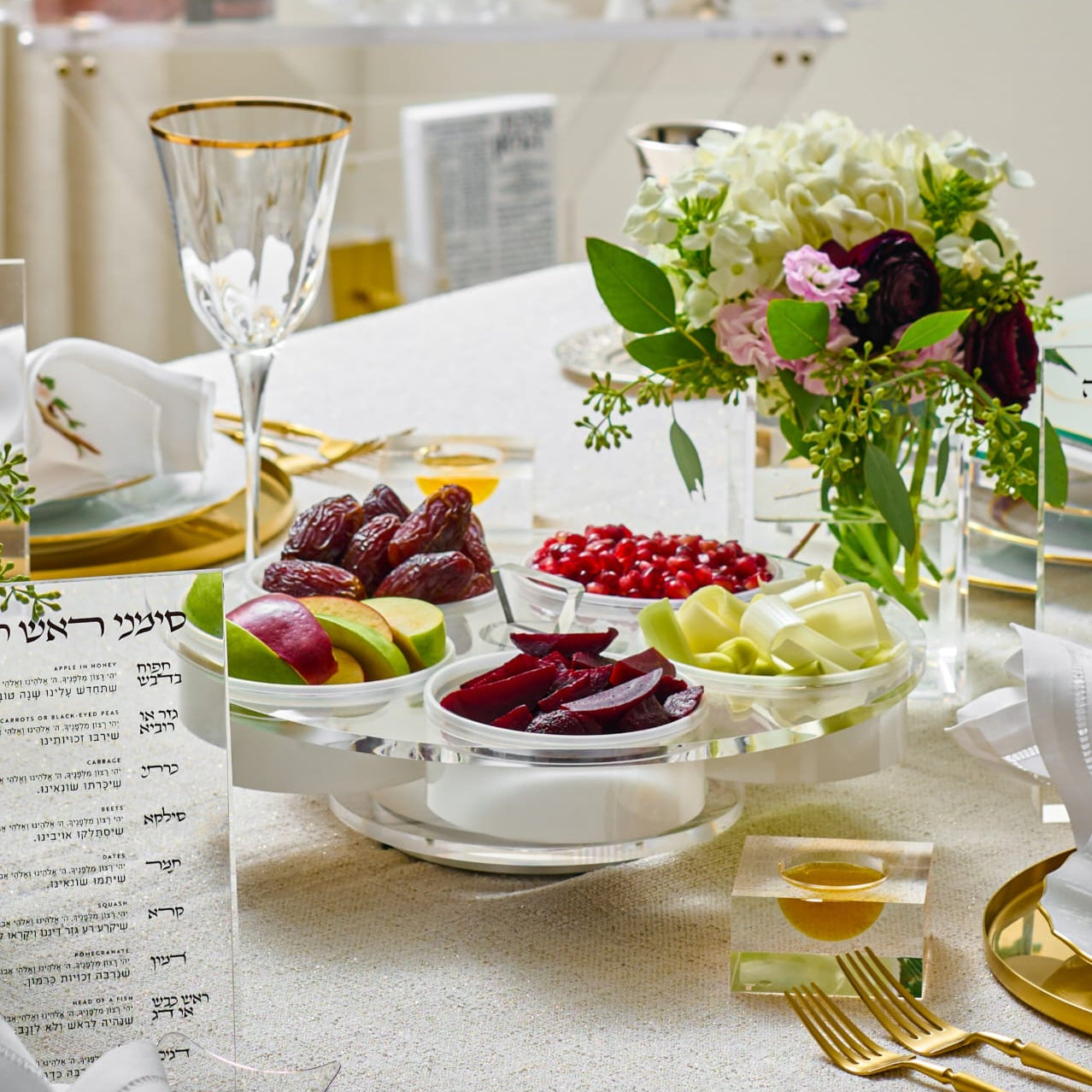 Elegant table setting with fruits, flowers, and gold cutlery on a light background