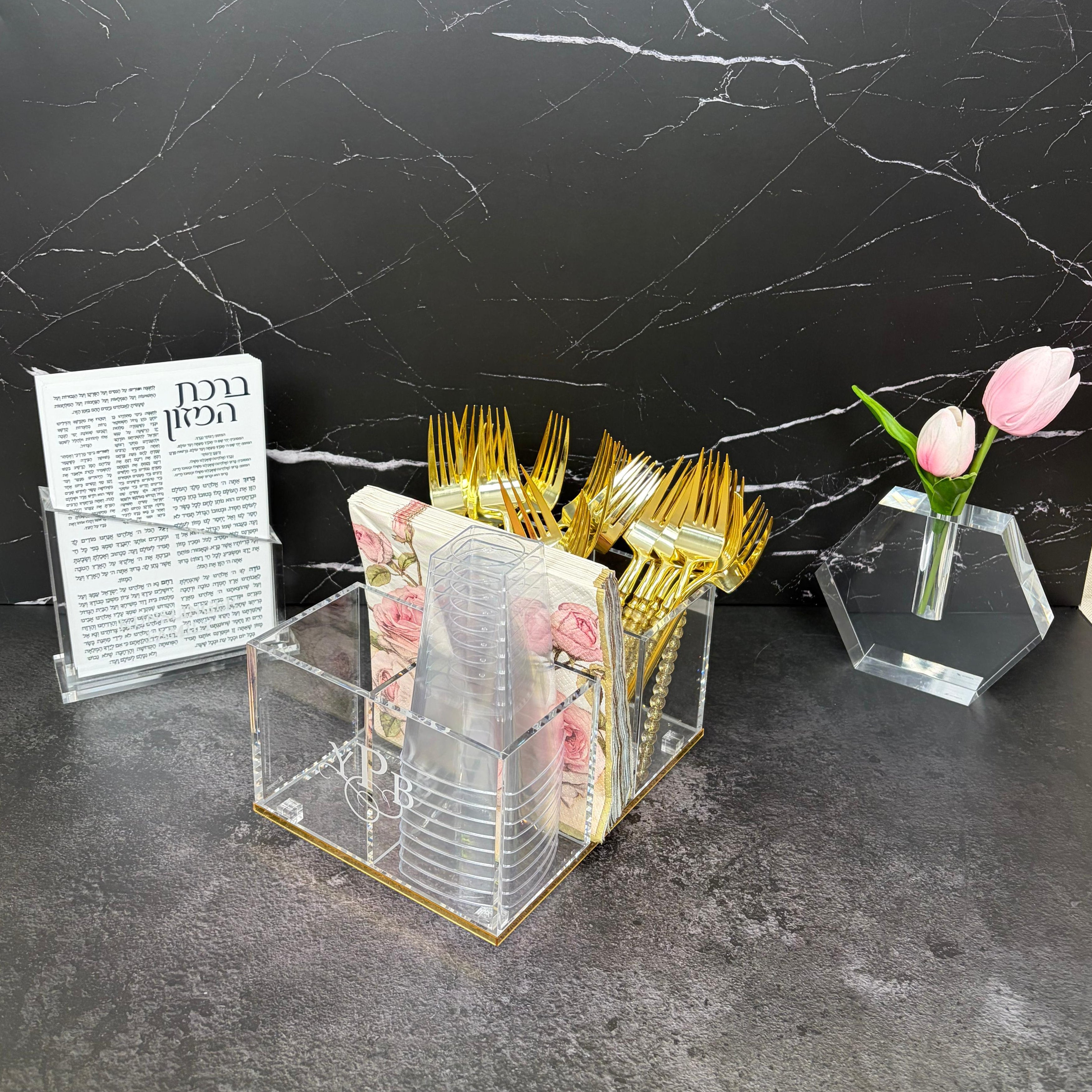 Decorative setup with gold forks, floral napkins, and a vase on a black marble surface - Zstander