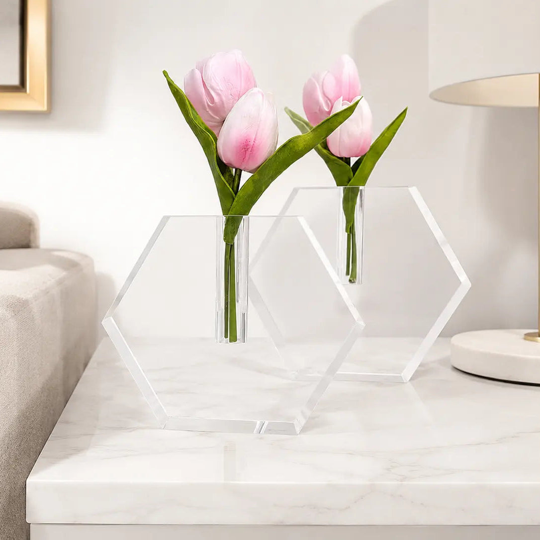 Clear geometric vase with pink tulips on a white surface in a living room setting -Zstander