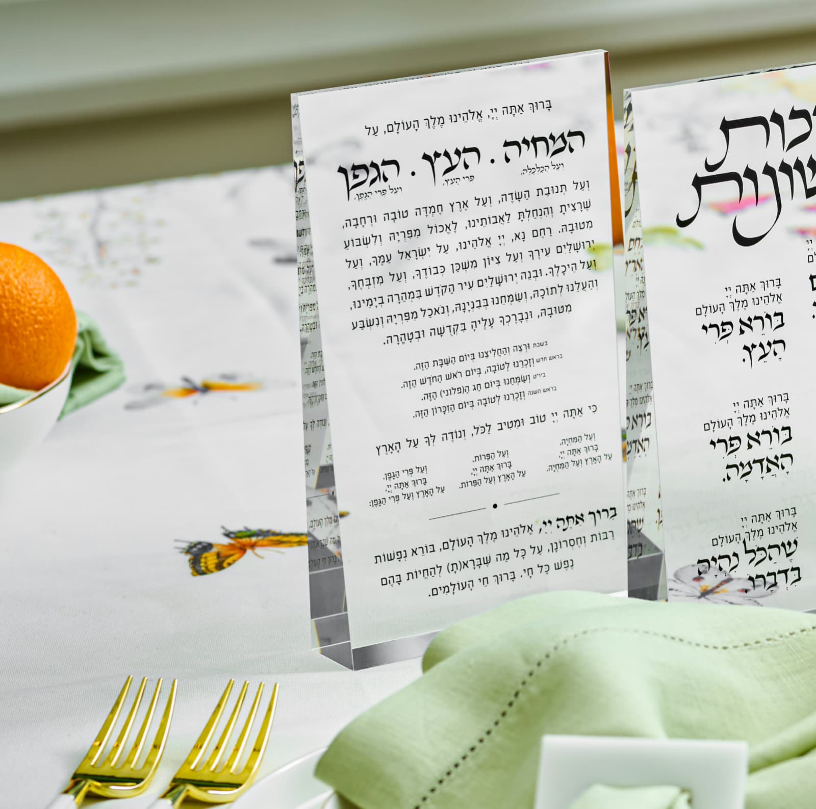clear prisim blocks with al hamichya text on a table setting with an orange and napkin - Zstander
