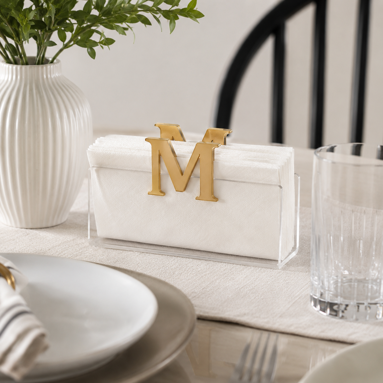 Dining table setting with a gold letter 'M' napkin holder white vase, and glass - Zstander