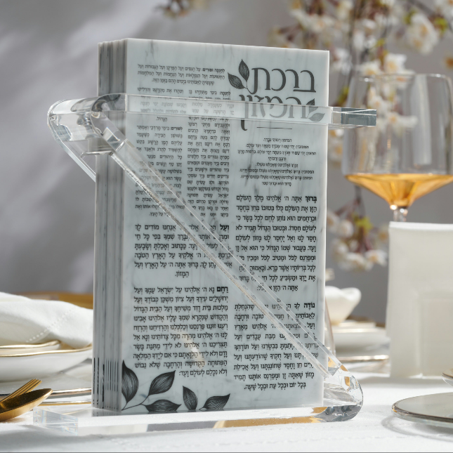 A clear lucite Z shaped holder with a marble-like pattern designed to hold a bencher, displayed on a set of tables with dishes and glasses, arranged for a meal - Zstander