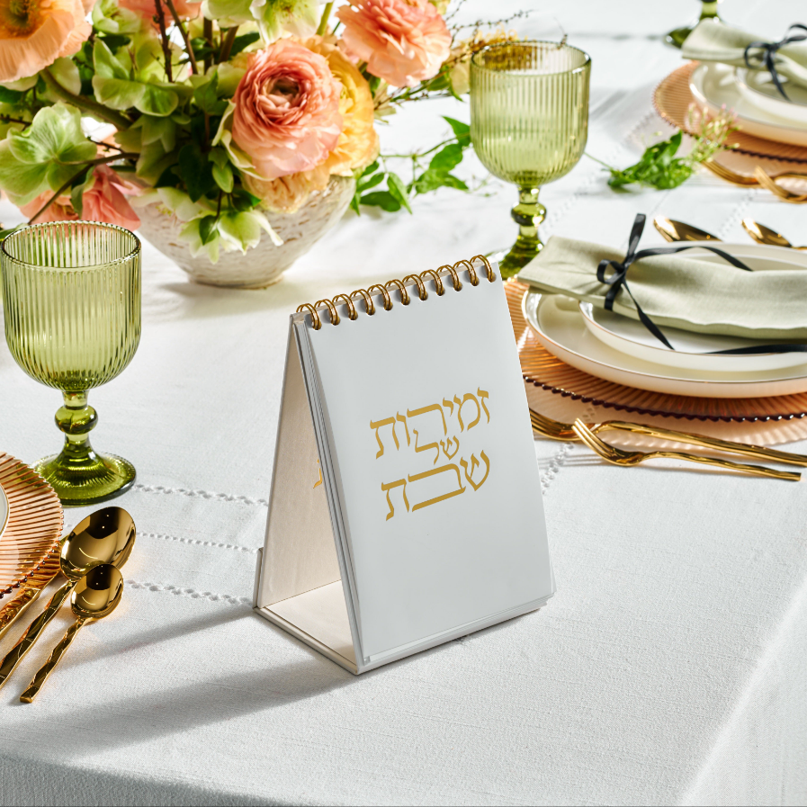 A spiral-top Zemiros with a leather design placed on a table with tableware, glasses, and a floral arrangement in the background - Zstander
