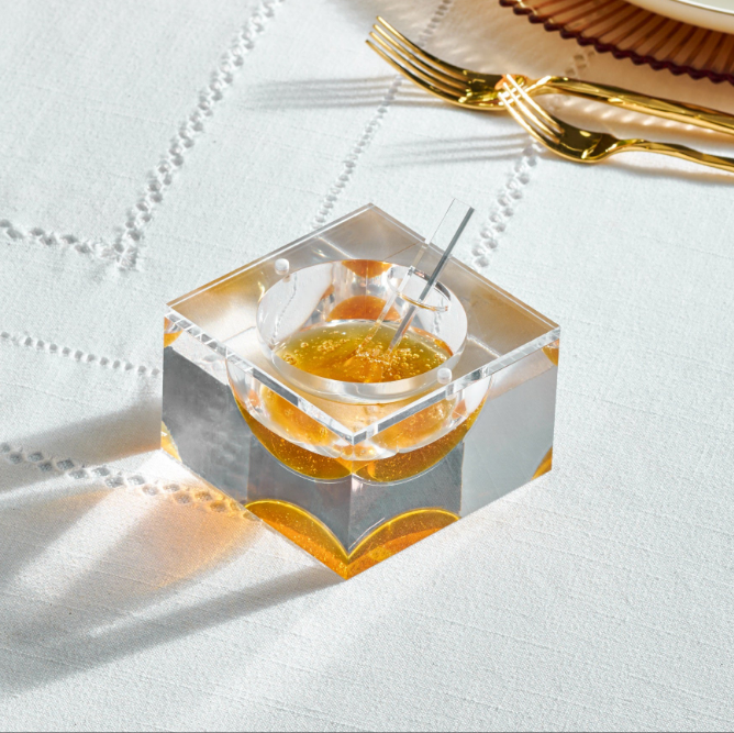 Clear square honey dish with honey on a white textured surface - Zstander