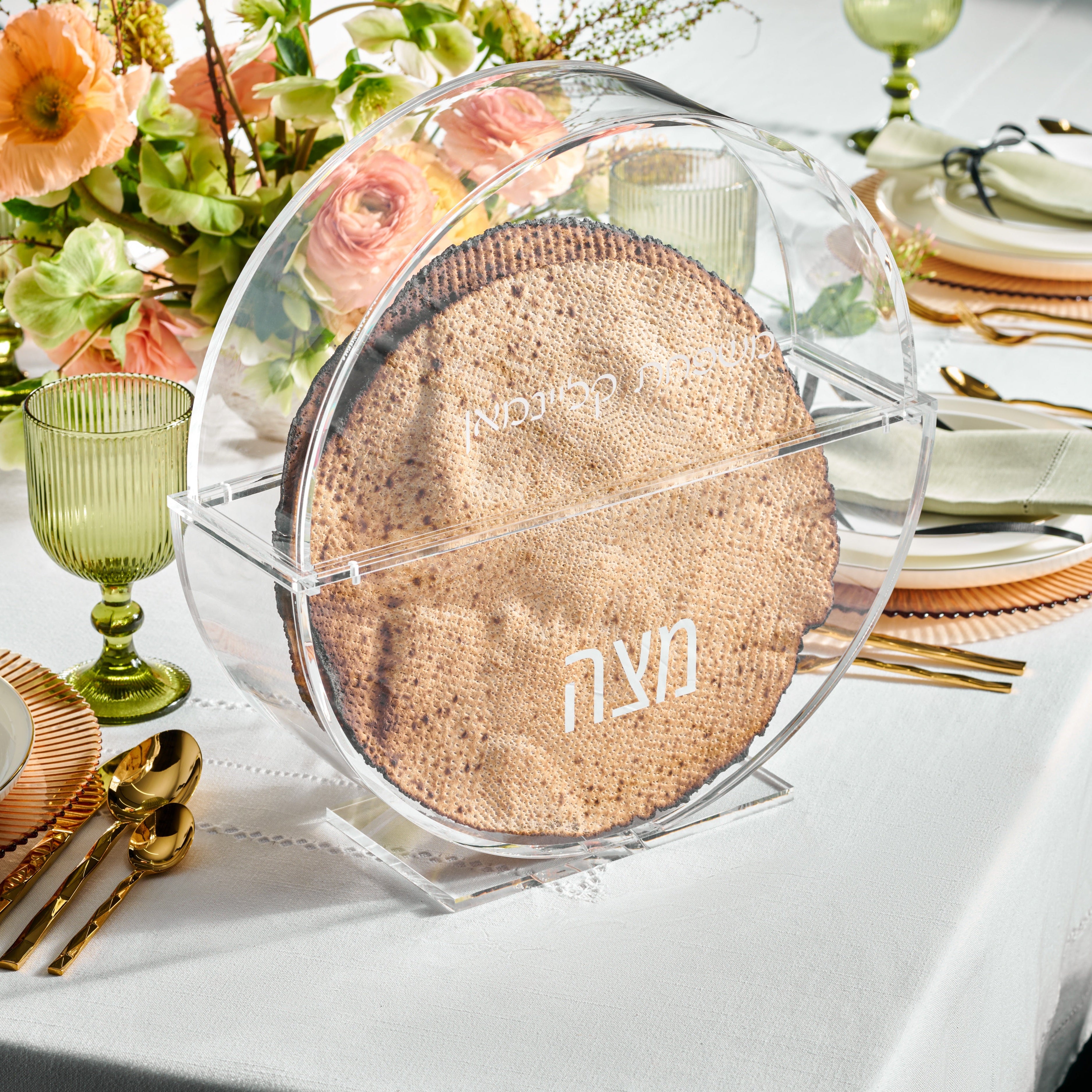 Clear round lucite matxah box on a set seder table, the word matzah at the bottom and family name engraved at the top - Zstander