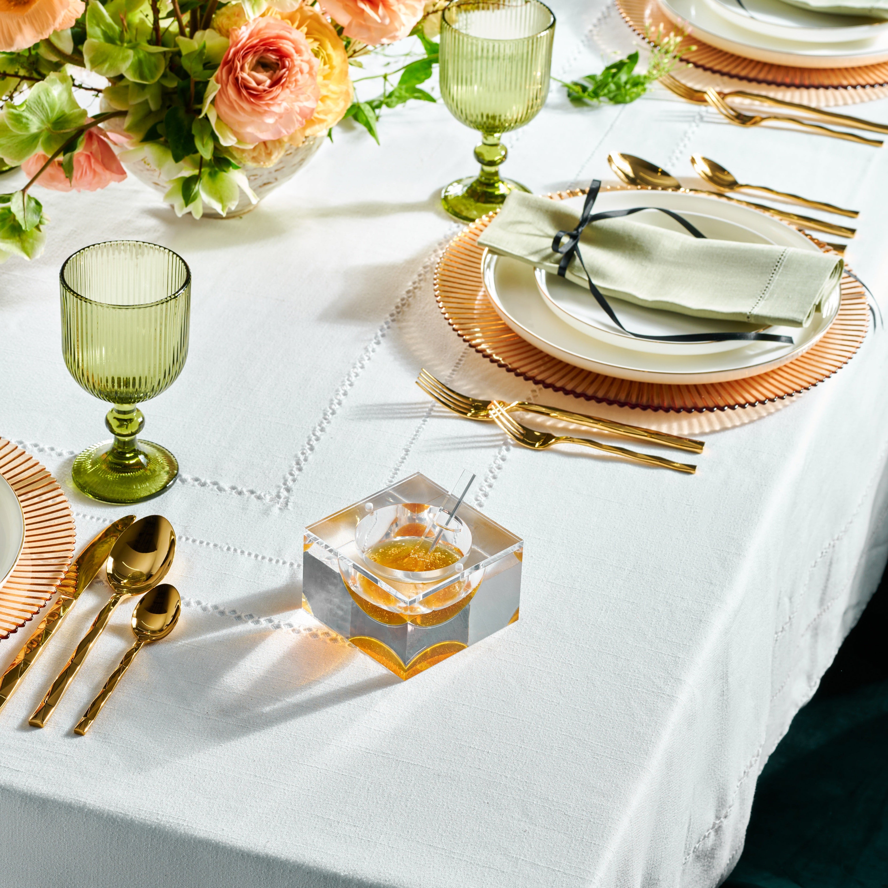 Elegant table setting with green glasses, gold cutlery, and floral centerpieces - Zstander