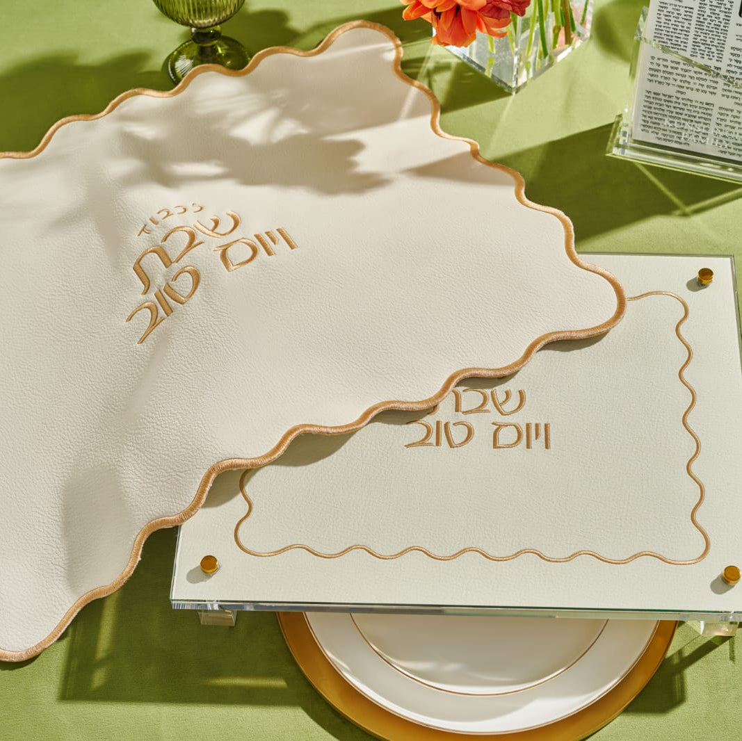 Decorative place setting with a challah board and cover and cutlery on a green tablecloth - Zstander