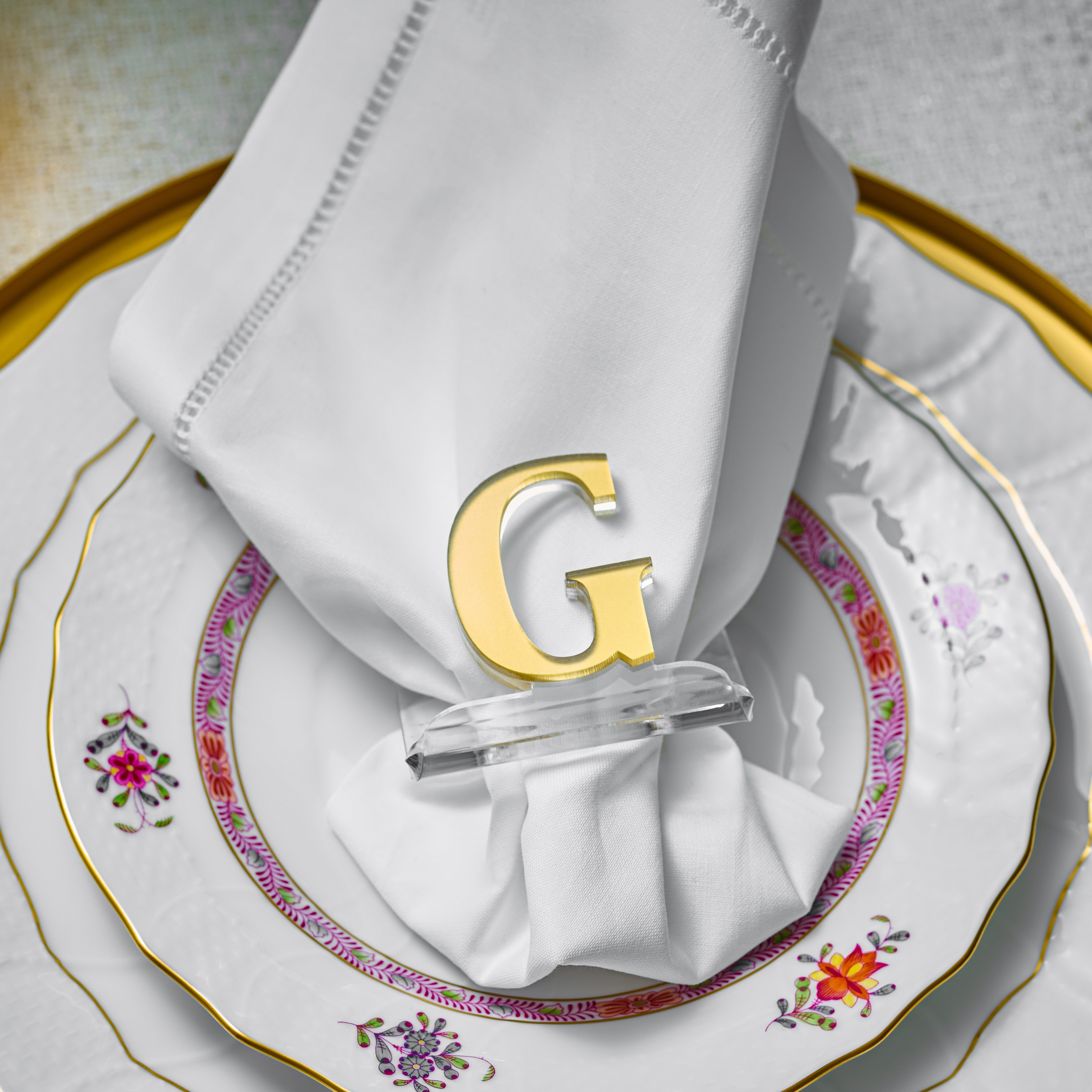 White napkin with gold letter 'G' napkin ring on a decorative plate - Zstander