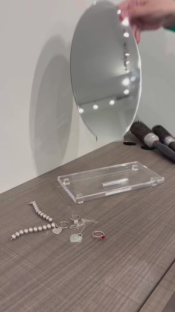 putting together a small vanity mirror on a brown desk. 