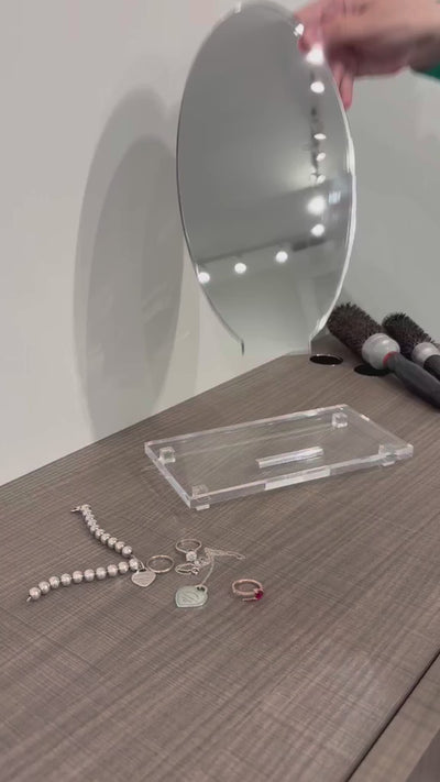putting together a small vanity mirror on a brown desk. 
