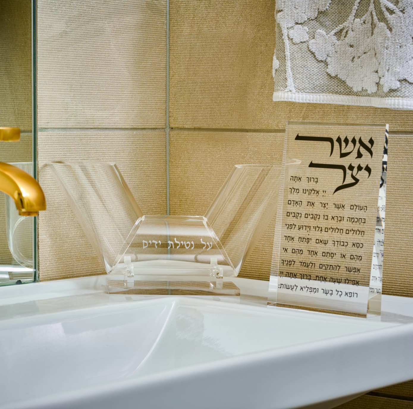 Clear acrylic dual spout washing cup and asher yatzar with religious text on a tiled wall background - Zstander